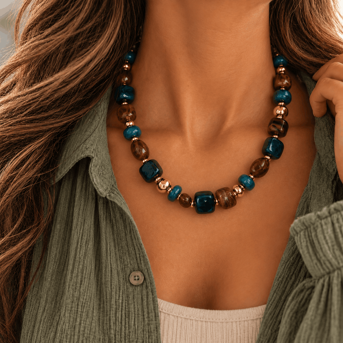 Blauwe Nola kralenketting met goudkleurige details gedragen om de pols van Hippe Kraal