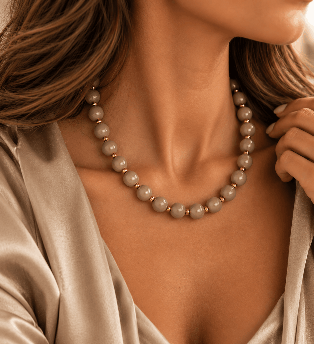 Taupe kralenketting gedragen om de hals bij een elegante outfit