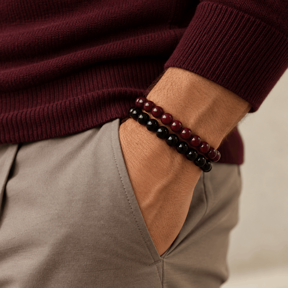 Essential herenarmbanden in zwart en burgundy gedragen bij een burgundy trui